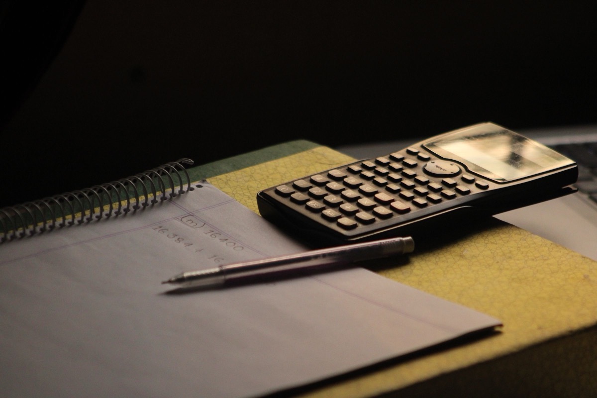 A calculator and a notebook on a dark desk