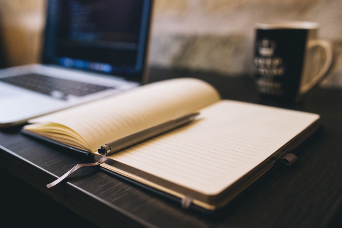 An open notebook and a pen on a wooden desk