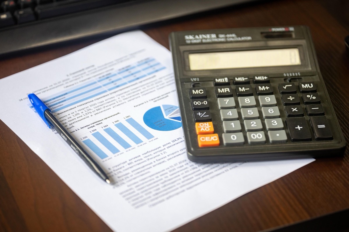 A printed report, a pen and a calculator on a desk