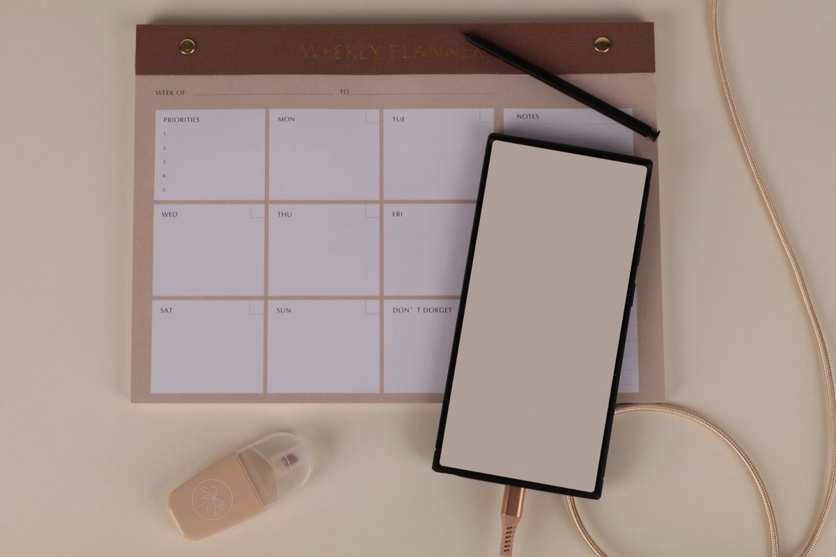 A blank planner and a phone on a beige desk