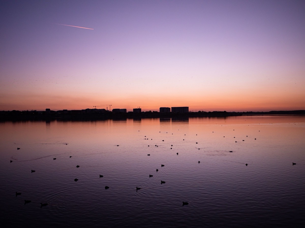 Sunset over a lake in Bucharest, the city skyline on the horizon