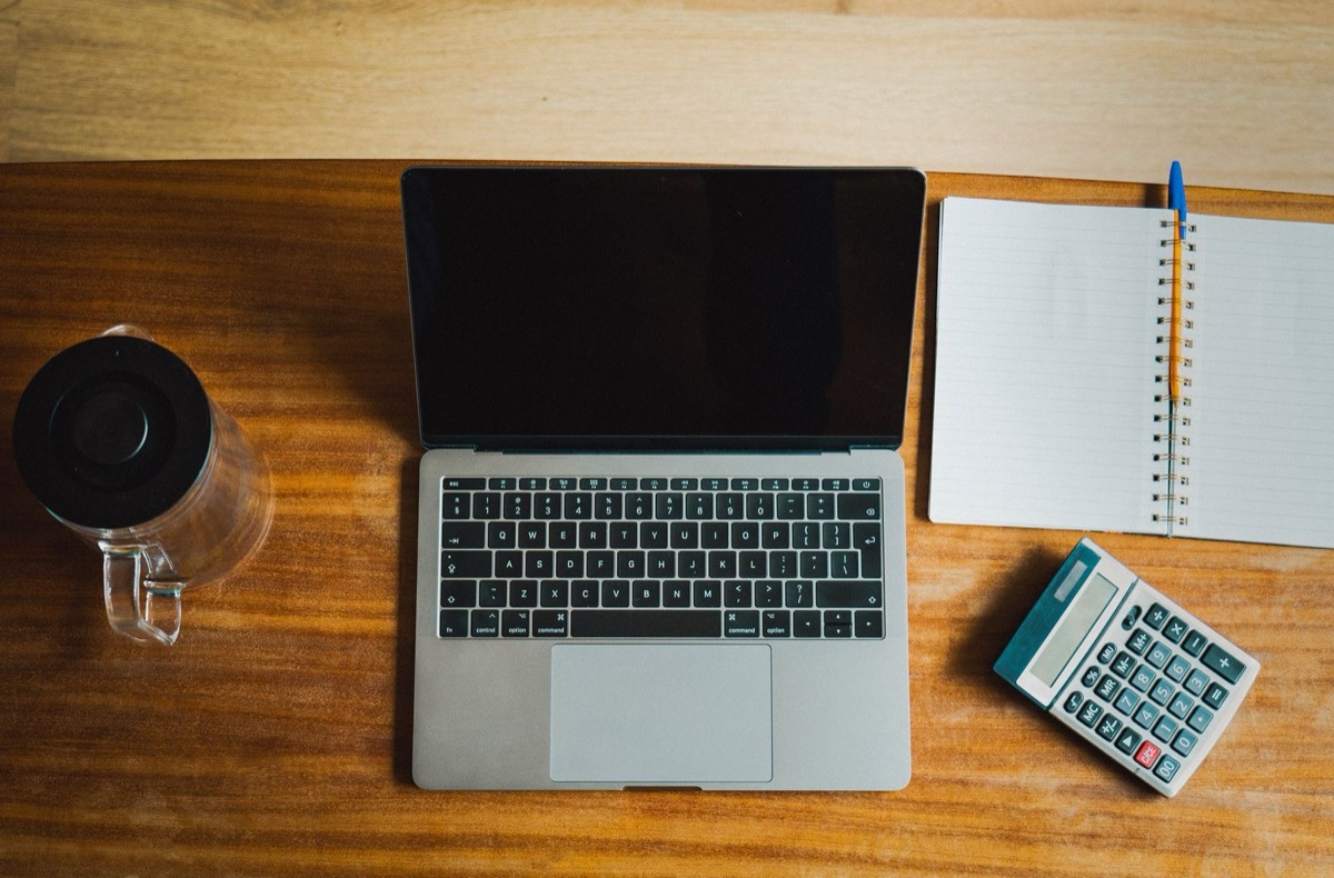 Accounting ledger, calculator and laptop on an office desk