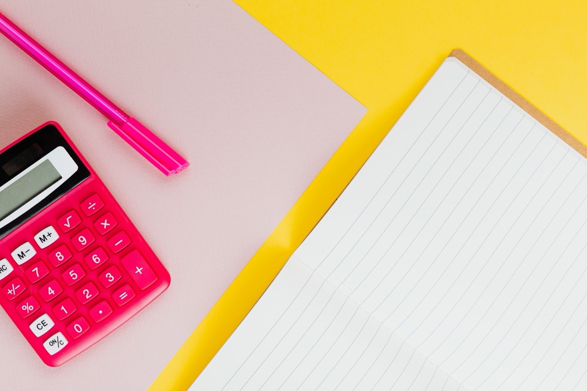 A calculator and a pen beside a lined notepad