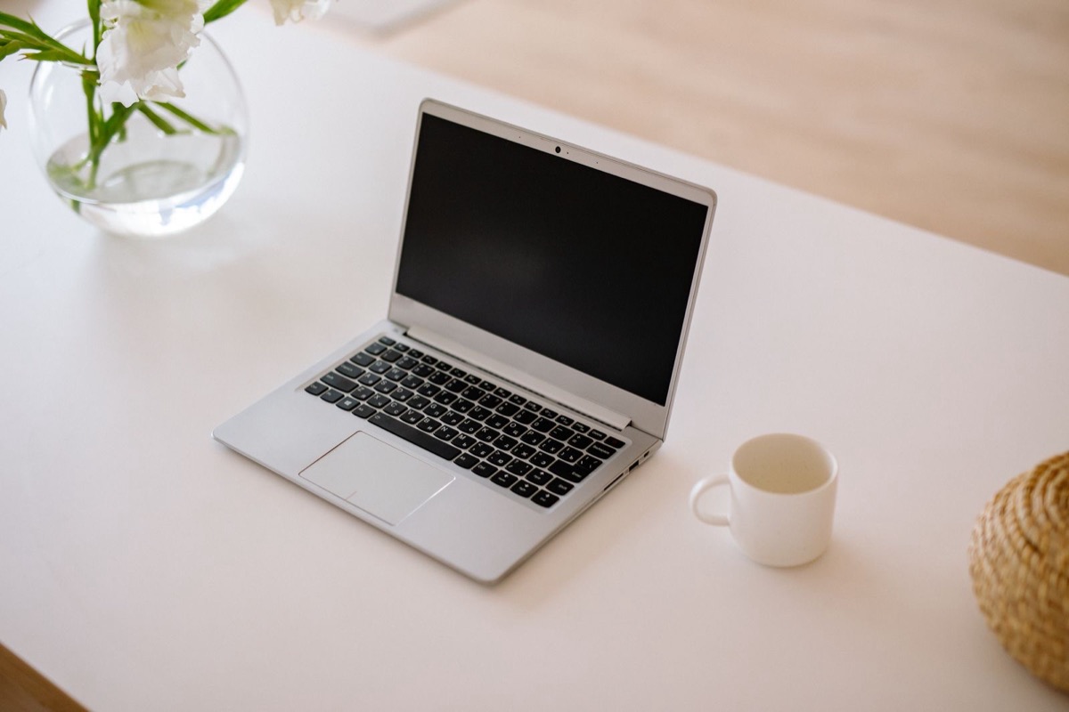 A laptop and a cup on a white desk