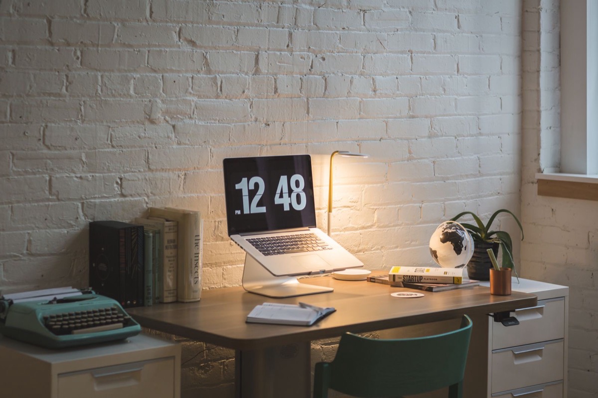 A small workspace with a laptop and a desk lamp